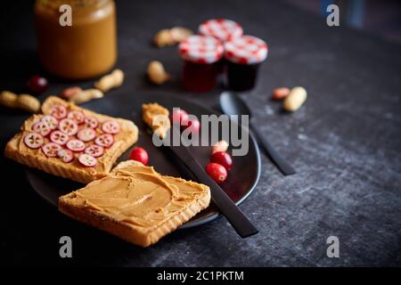 Toasts de pain avec beurre de cacahuète fait maison servi avec des tranches de canneberges fraîches Banque D'Images