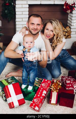 Positivity family posing ensemble près de cheminée et présente pour Noël Banque D'Images