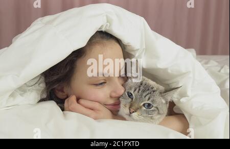 Happy teen girl baisers et des pourparlers avec Thai cat in bed Banque D'Images