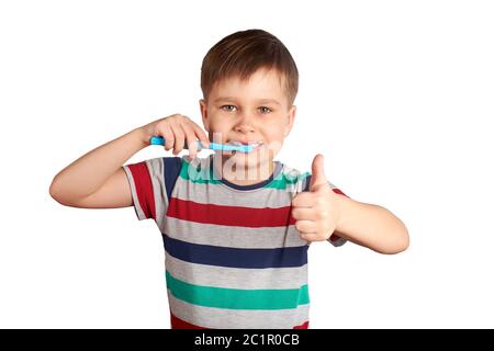 Un garçon souriant se brosse les dents et montre un pouce vers le haut, isolé sur un fond blanc. Banque D'Images