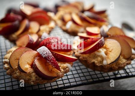 Tartelettes crumble fait maison avec des tranches de prune mis sur la cuisson grill fer Banque D'Images