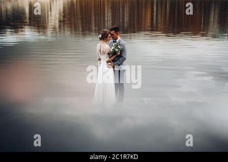 Mariée en couple whire et nettoyer en gris au milieu du lac. Banque D'Images