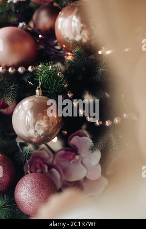 Arbre de Noël avec des arcs et des rubans à carreaux roses et humeur de fête près de cheminée. Banque D'Images