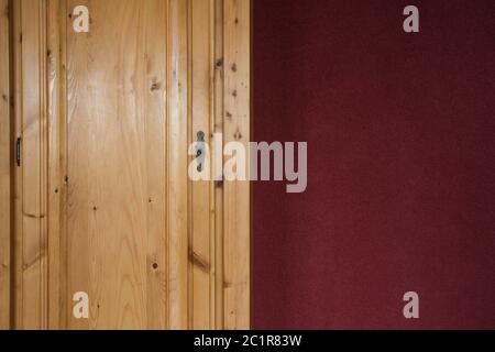 Portes de placard en bois brun close up avec mur bordeaux rouge Banque D'Images