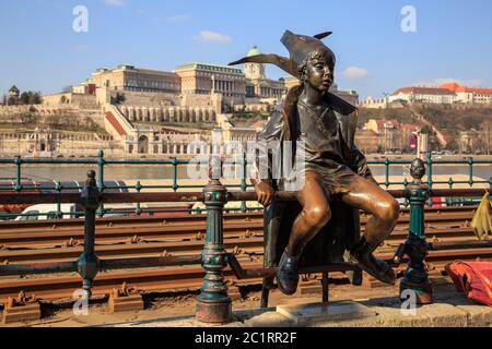 Budapest, Hongrie, mars 22 2018 : statue d'un enfant assis avec un chapeau près du rail de tram sur les rives du Danube Banque D'Images