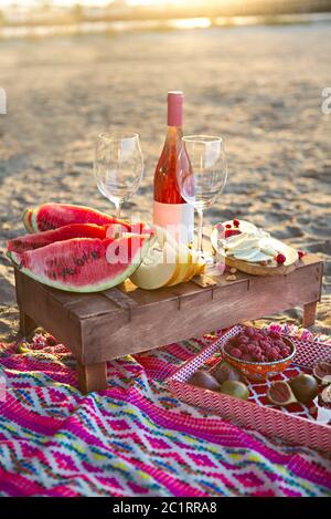 Pique-nique sur la plage avec vin de rose, fruits, viande de noix et fromage Banque D'Images