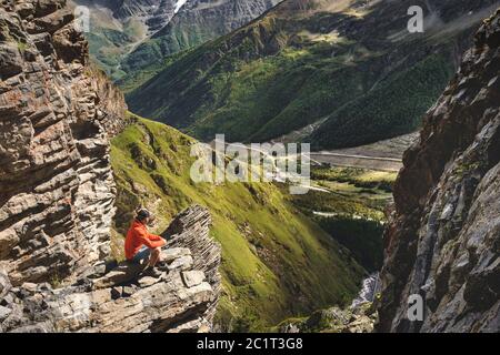 Portrait d'un randonneur mâle en short et d'un chapeau de l'arrière est debout sur de hautes roches au bord d'une falaise contre le backgrou Banque D'Images