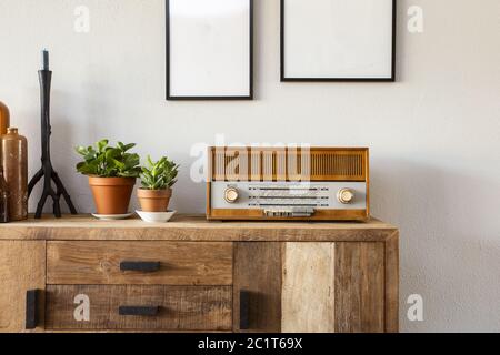 Salon rétro avec le cabinet de design et radio ainsi que des plantes vertes et tableaux vierges, mur blanc Banque D'Images