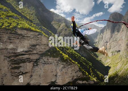 Un homme dans un casque saute en haut avec un drapeau vide dans les montagnes. Sports extrêmes. Loisirs Banque D'Images