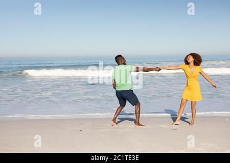 Couple de course mixte dansant sur la plage Banque D'Images