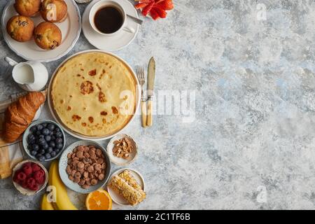 Table de petit déjeuner avec des fruits frais, des crêpes, du café, des croissants Banque D'Images