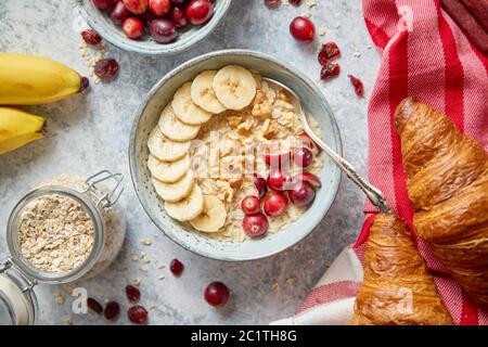 Bol de gruau en céramique du porridge à la banane, noix et canneberges fraîches Banque D'Images