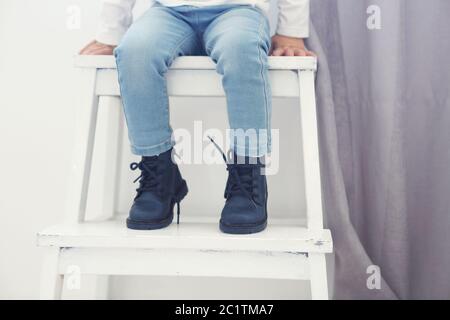 Joli petit bébé élégant dans des chaussures en cuir assis sur la chaise. Banque D'Images