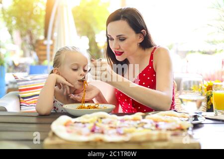 Bonne mère et fille mangeant spaghetti bolognaise dans le restaurant Banque D'Images