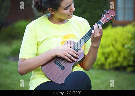 Adorable jeune fille jouant à son ukulele à l'extérieur Banque D'Images