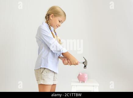 Petite fille avec marteau par la banque de porc rose Banque D'Images