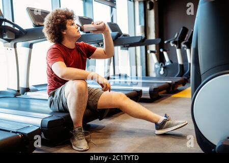 Surpoids jeune homme exerçant dans la salle de gym pour atteindre les objectifs Banque D'Images