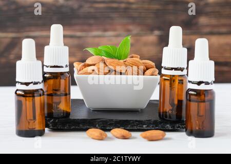 amandes en plaque blanche et bouteilles de verre avec huile sur un plateau noir sur une table en bois Banque D'Images