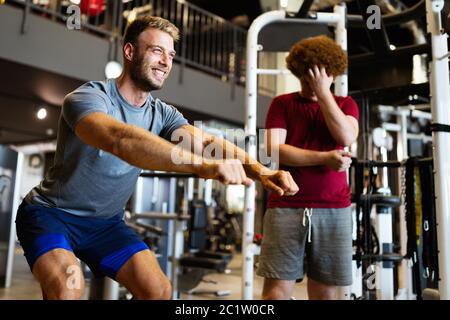 Surpoids jeune homme faisant de l'exercice de salle de gym avec entraîneur personnel Banque D'Images