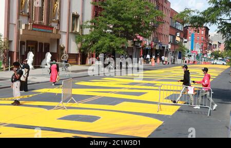 New York, États-Unis. 15 juin 2020. Les gens marchent devant les mots « Black Lives Matter » peints en jaune vif sur une partie de la 16e rue renommée Black Lives Matter Plaza à Brooklyn de New York, aux États-Unis, le 15 juin 2020. Crédit : Wang Ying/Xinhua/Alay Live News Banque D'Images