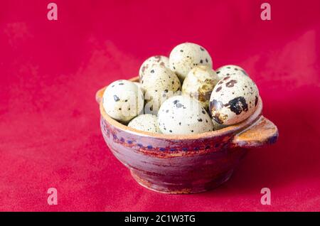 Oeufs de caille en cuvette d'argile, fond rouge Banque D'Images