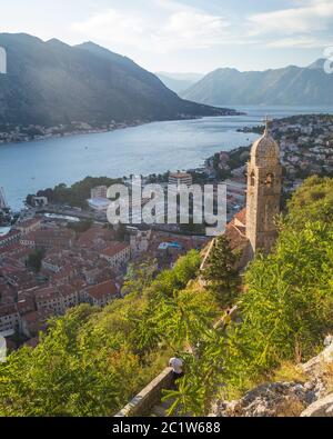 KOTOR, MONTÉNÉGRO - 12 AOÛT 2016 : vue panoramique sur la ligne d'horizon de Kotor autour du coucher du soleil. Partie de l'Église de notre-Dame de Remedy, montagnes et gens Banque D'Images