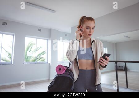 Danseuse de ballet caucasienne regardant son téléphone avec écouteurs Banque D'Images