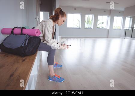 Danseuse de ballet caucasienne regardant son téléphone avec écouteurs Banque D'Images