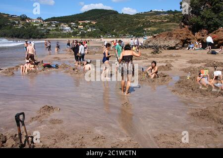 COROMANDEL, NOUVELLE-ZÉLANDE - 11 MARS 2008 : les touristes creusent leurs propres sources d'eau chaude à Hot Water Beach, Coromandel, Nouvelle-Zélande. Banque D'Images