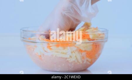 La fille prépare de la viande hachée. La main féminine ajoute des carottes, des oignons à la viande hachée et mélange. Plats à base de viande Banque D'Images