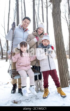 La neige sur les balançoires de famille heureuse Banque D'Images