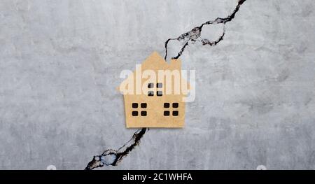 Maison miniature sur fond de texture de mur de ciment fissuré. Vue de dessus Banque D'Images
