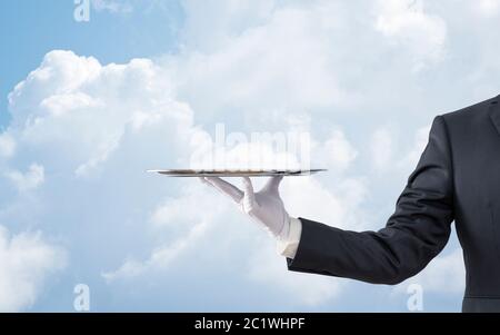 Waiter holding empty silver tray plus de ciel bleu Banque D'Images