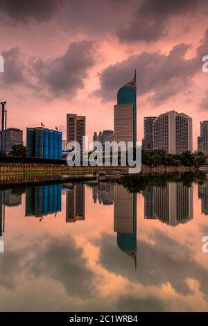 Horizon de Jakarta sous ciel nuageux. Bureaux tour de la ville de Jakarta réfléchi sur l'eau avec des nuages sur le ciel Banque D'Images