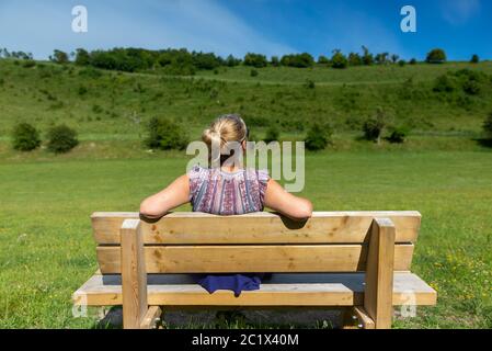 Femme assise sur un banc sous le soleil d'été à Coombe Bishissed bas de la réserve naturelle, Salisbury, Wiltshire, Royaume-Uni Banque D'Images