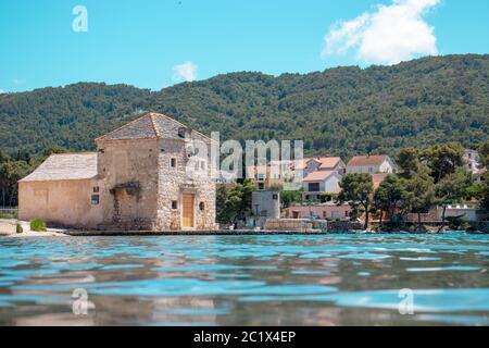 Petite maison pittoresque de Saint Jerolim, bâtiment en pierre de style grec, situé sur le front de mer de Starigrad, Hvar. Vue de la mer Banque D'Images