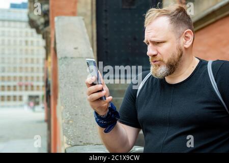 homme adulte mal surpris en regardant un smartphone dans un centre-ville. homme ont de mauvaises nouvelles sur smartphone Banque D'Images