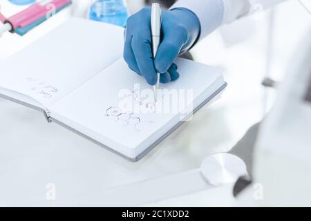 gros plan. une scientifique féminine écrit des résultats de recherche dans un cahier. Banque D'Images