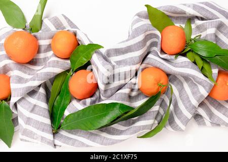 Mandarines sur une serviette en lin rayée sur fond blanc Banque D'Images