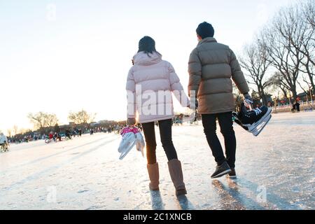 Jeunes couples avec patins à la patinoire Banque D'Images