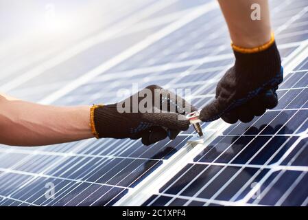 Gros plan des mains de M. en gants noirs avec une clé dans ses mains pour installer des panneaux solaires. Concept: Énergie renouvelable, technologie, électricité, service, énergie verte. Banque D'Images