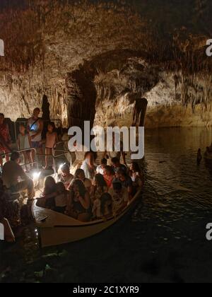 Touristes se rendant sur un voyage en bateau dans une grotte de calcaire inondée avec de nombreuses stalactites et stalagmites, grottes de Drach / Cuevas del Drach, Porto Banque D'Images