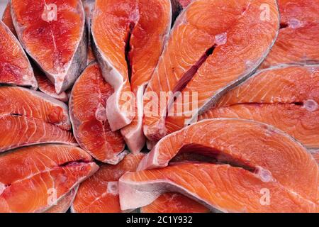 Beaucoup de morceaux de saumon quinnat du poisson rouge du Pacifique cru coupé dans le steak et prêt à cuire divers plats délicieux. Vue rapprochée de la couche plate du poisson frais Banque D'Images