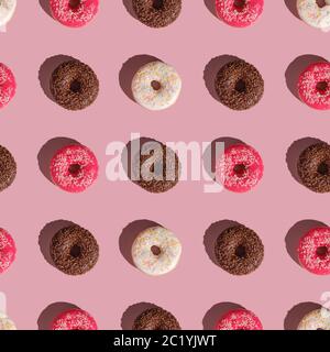 Beignets roses, vanille et chocolat avec saupoudrer, motif sans couture, dessert glacé sucré sur fond rose minimal, vue du dessus Banque D'Images