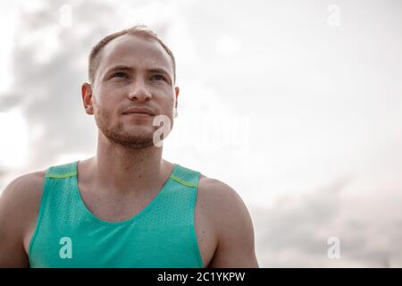 Portrait of Caucasian guy dans un azure t-shirt et short noir en marche sur terrain accidenté. formation pendant le coucher du soleil Banque D'Images