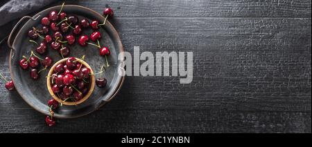 Plateau, surface et tasse vintage métallisé avec cerises juteuses rouges à l'intérieur de la tasse et dispersées autour du plateau - Haut de la vue Banque D'Images