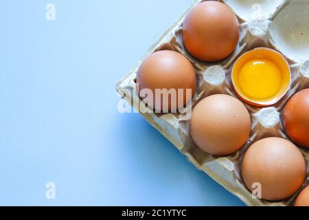 L'œuf de poulet est à moitié cassé parmi les autres œufs. Œufs bruns et jaune d'œuf Banque D'Images