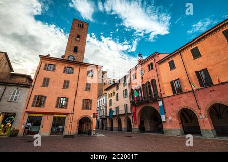 Vieilles maisons colorées et tour médiévale sur la place pavée de la ville d'Alba, Piémont, Italie du Nord. Banque D'Images