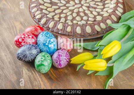 Les oeufs de Pâques colorés, tulipes et de gâteau de Pâques sur table en bois Banque D'Images