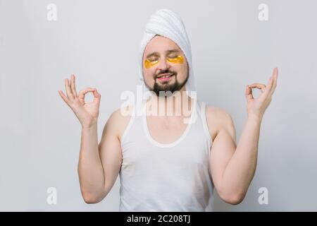 Portrait d'un beau barbu debout avec les yeux fermés, serviette sur la tête et les taches dorées sous la zone des yeux, ayant la détente tout en méditant Banque D'Images
